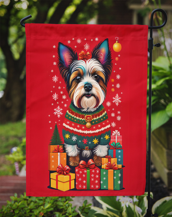 Red garden flag hanging outdoors, featuring terrier in holiday sweater with gift boxes