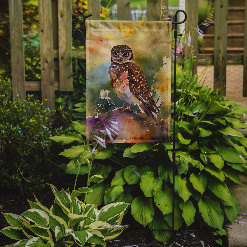 Burrowing owl garden flag displayed on a metal stake among green plants