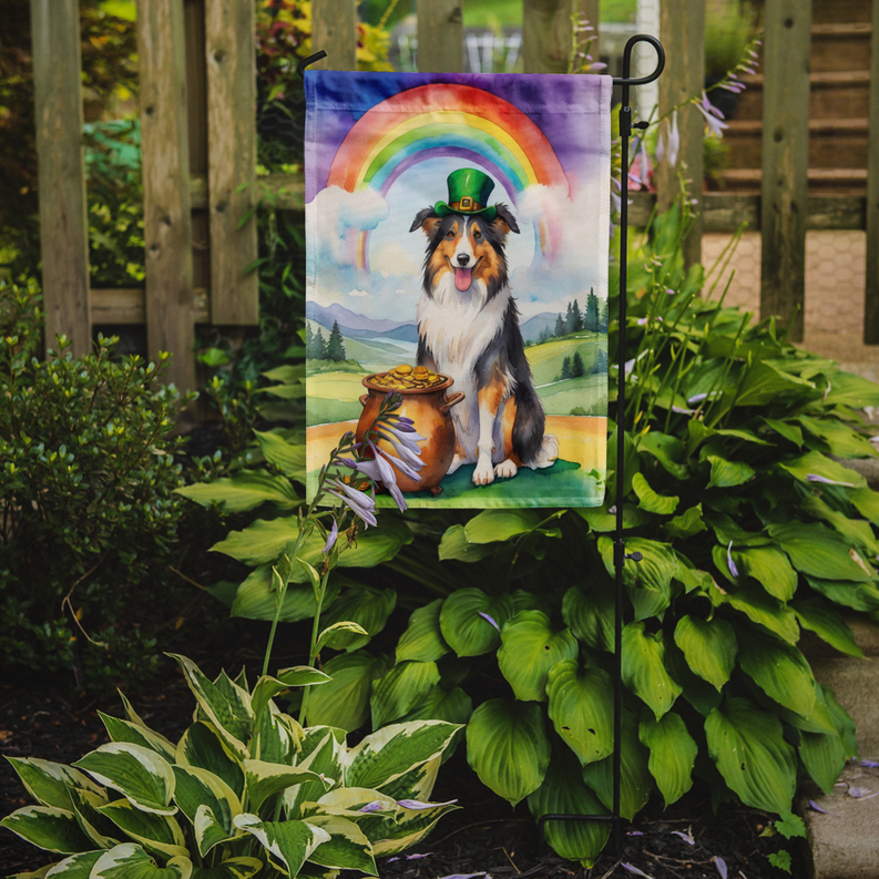 Garden flag on outdoor stand featuring collie with green hat, rainbow, and gold pot