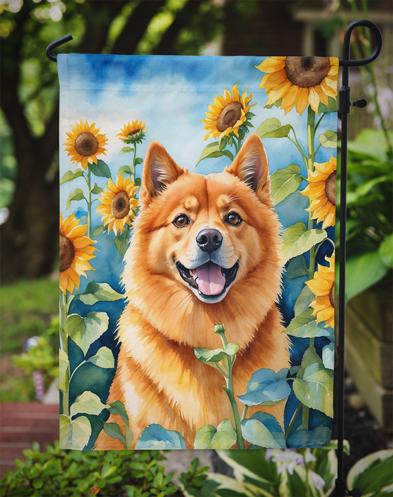 Garden flag featuring an orange Finnish Spitz in a sunflower garden with blue sky background.