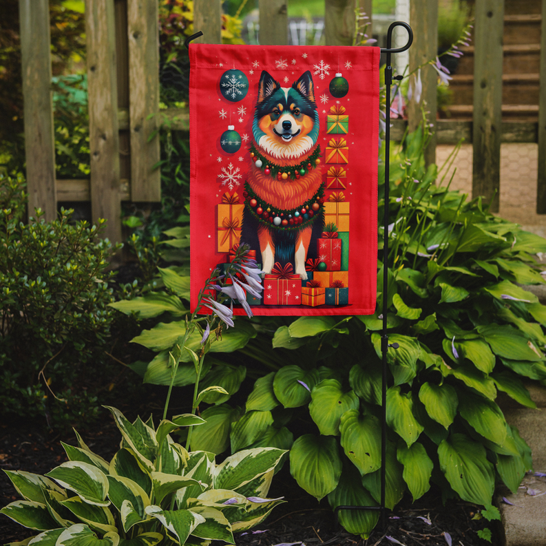 Red Christmas garden flag on fence stake, Finn lapphund with wreath and wrapped gifts