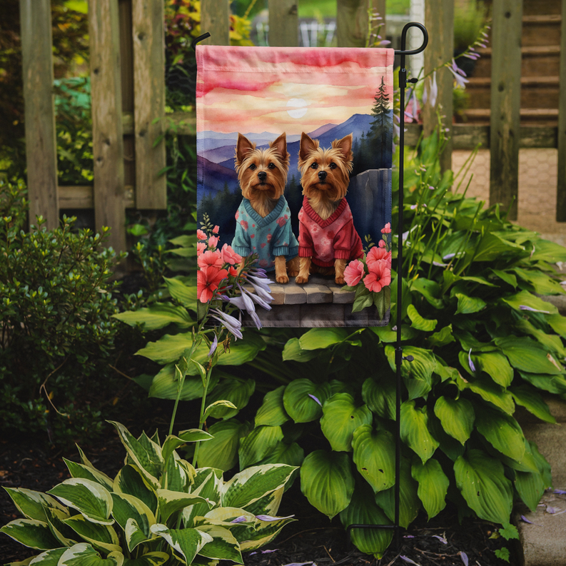 Garden flag with two terriers in blue and pink sweaters among flowers in a yard