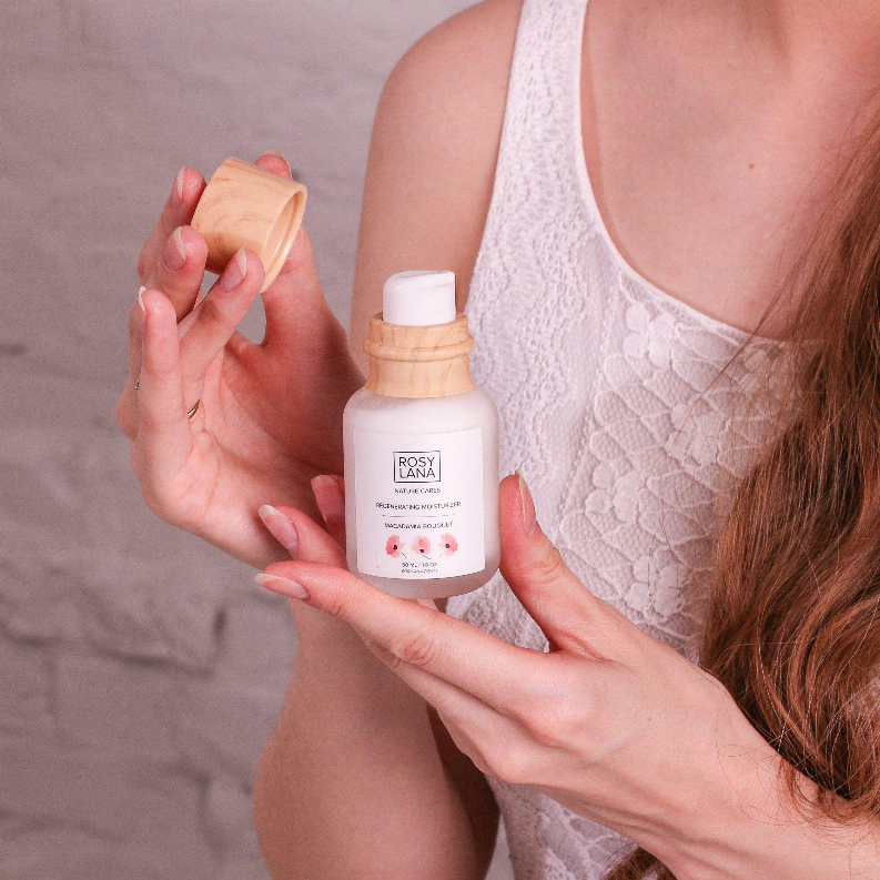 Moisturizer bottle held near face with wooden cap and white label