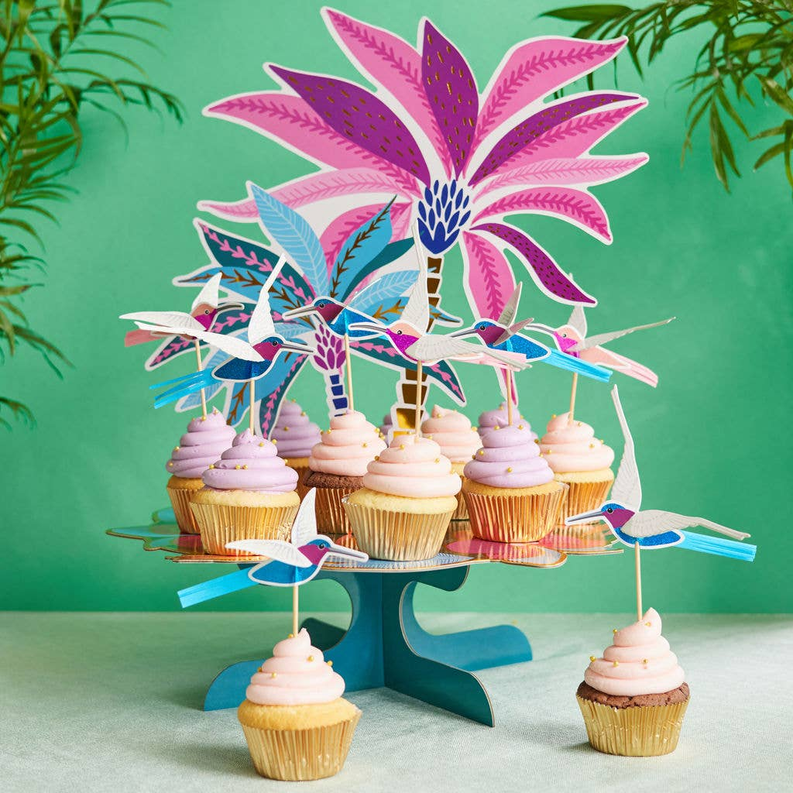 Set of tropical bird cupcake toppers on a tiered stand with many frosted cupcakes