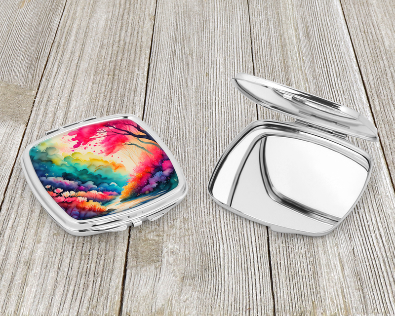 Compact mirror open flat with silver interior and colorful floral landscape on lid