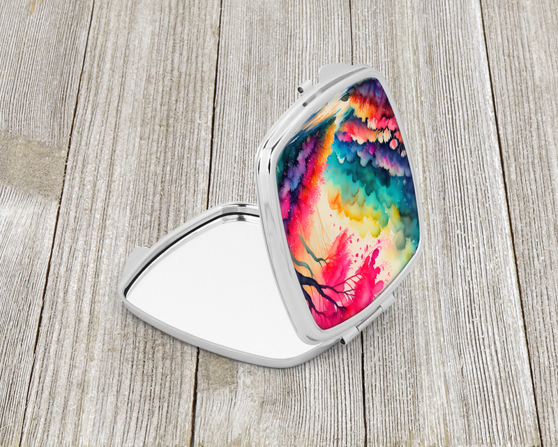 Folded compact mirror with silver frame and colorful rainbow landscape design on top