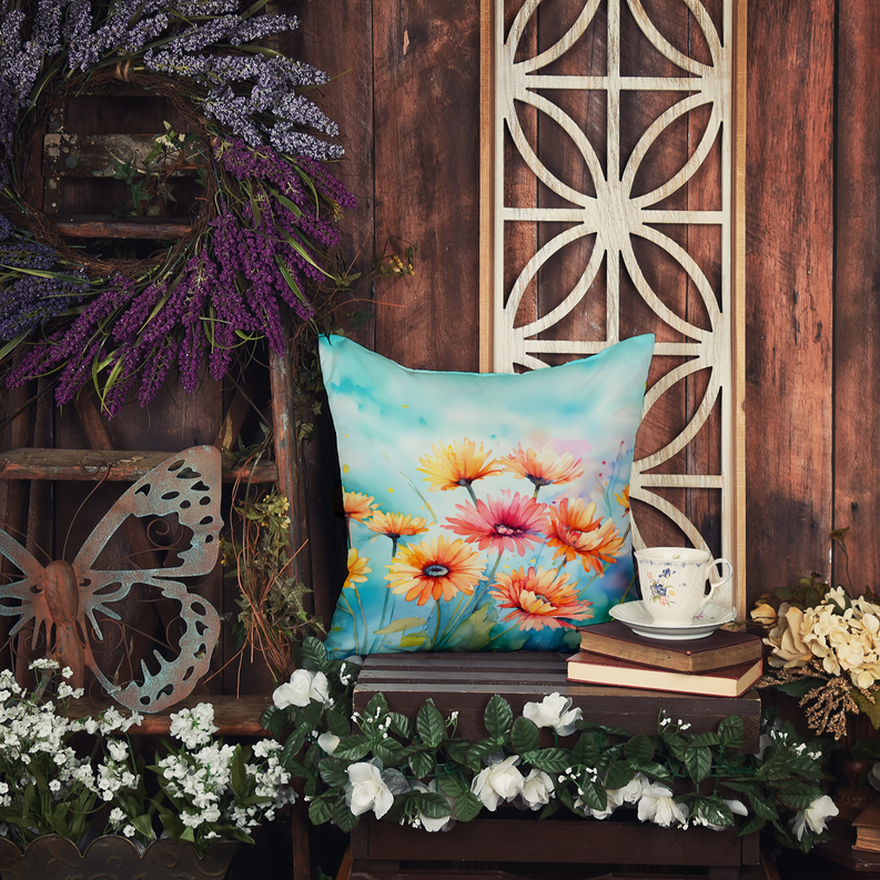 Watercolor floral throw pillow with multicolor gerbera-style blossoms on a bench.