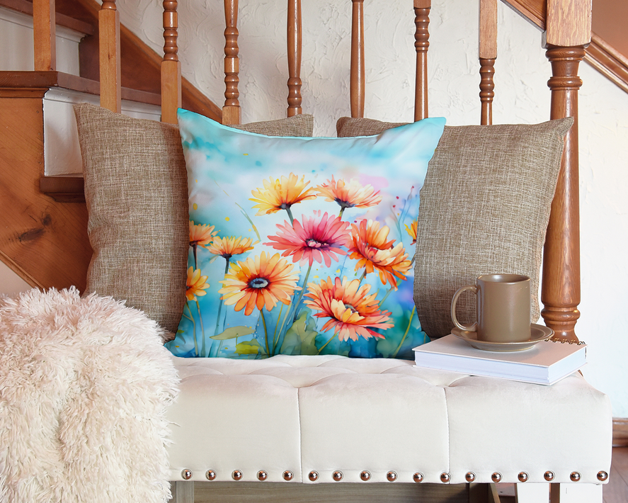 Watercolor floral throw pillow with colorful gerbera-style blossoms on a cushioned seat.