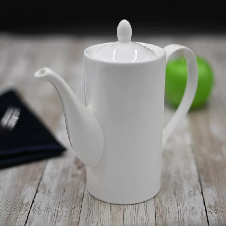 White coffee pot with lid knob and curved pouring spout on a wooden surface