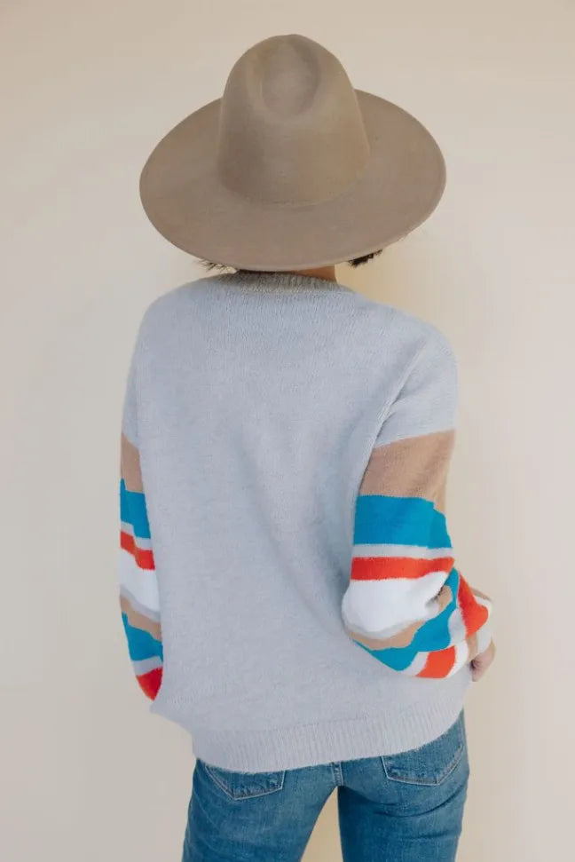 Back view of light gray crewneck sweater with multicolor striped sleeves