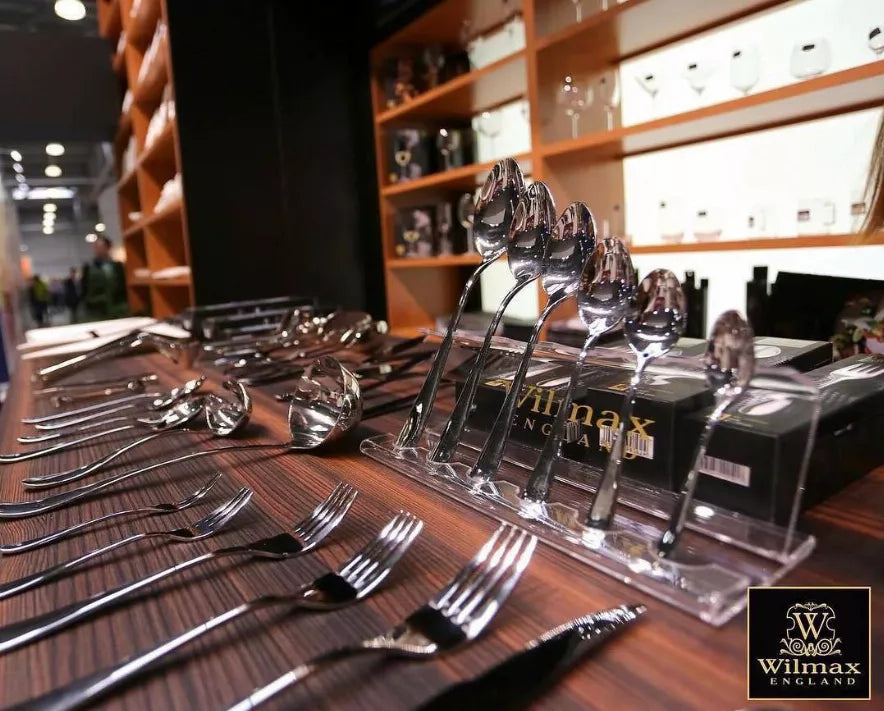 Stainless steel steak knife set arranged on a counter with matching forks and holders.