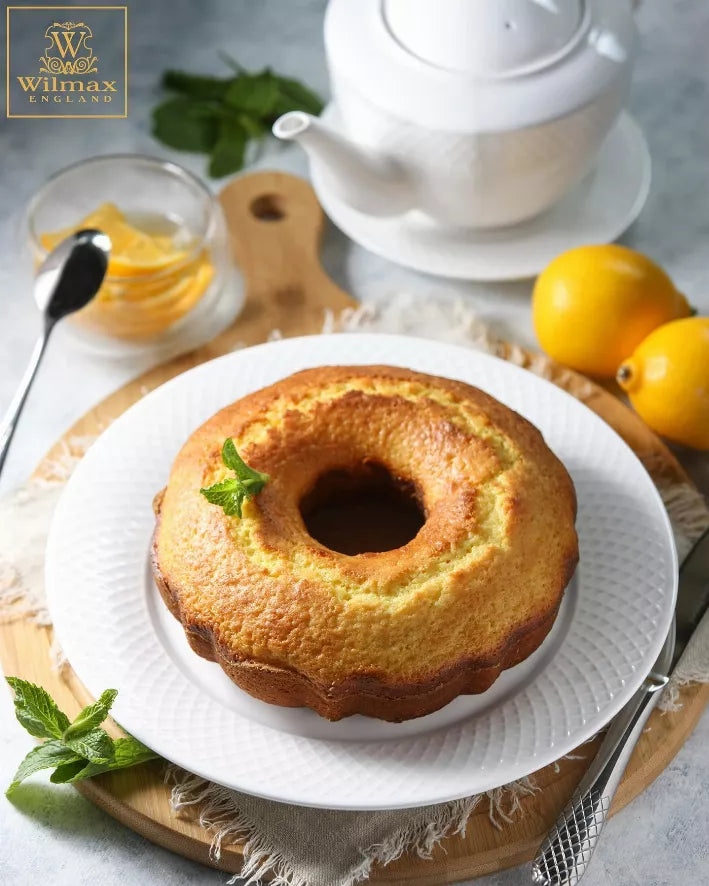 White embossed dinner plate with textured rim, holding a bundt cake slice