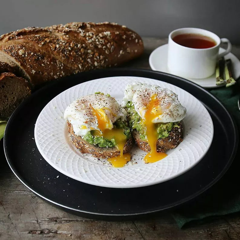 White embossed dinner plate with textured rim, topped with eggs and vegetables