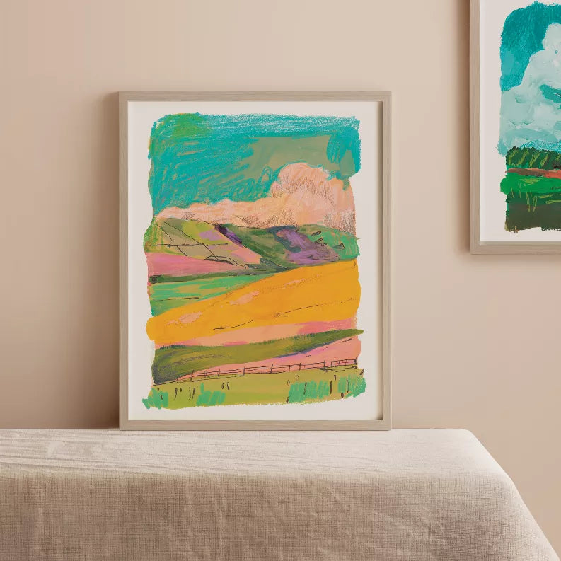 Framed abstract hills art print in teal, peach, purple, and yellow with green foreground