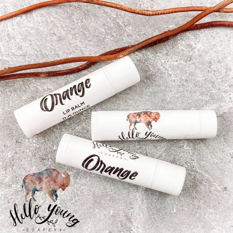 Orange lip balm tubes with white caps, printed logos and horse graphics on labels