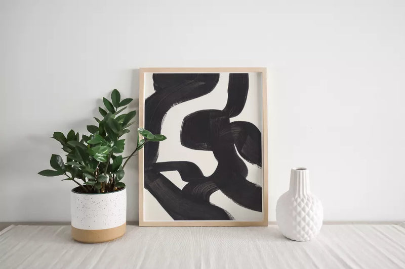 Framed abstract ink art print with black brush strokes on a light background.