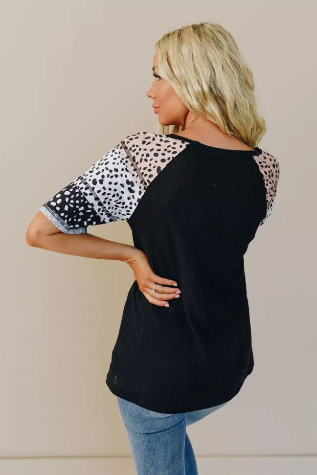 Black short-sleeve top with white spotted sleeves, back view