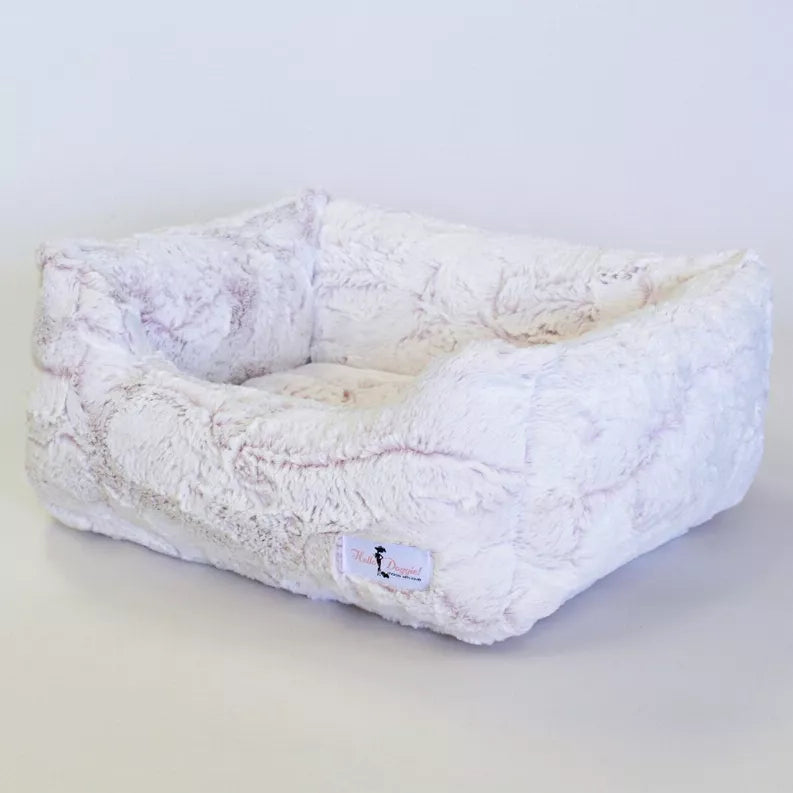 Light lavender plush dog bed with raised bolster and soft cushioned interior