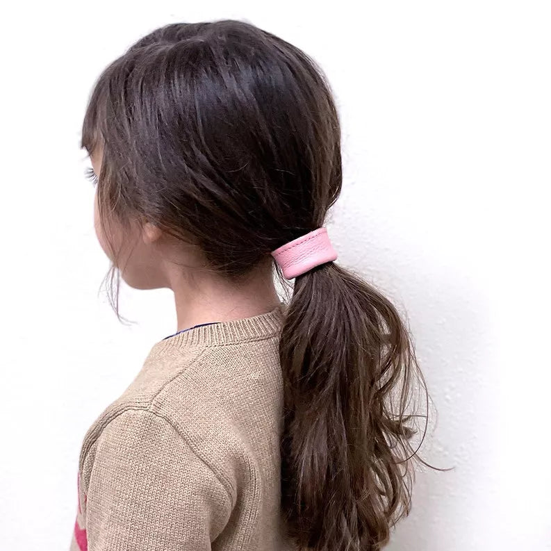 Light pink leather hair tie wrapped around a ponytail