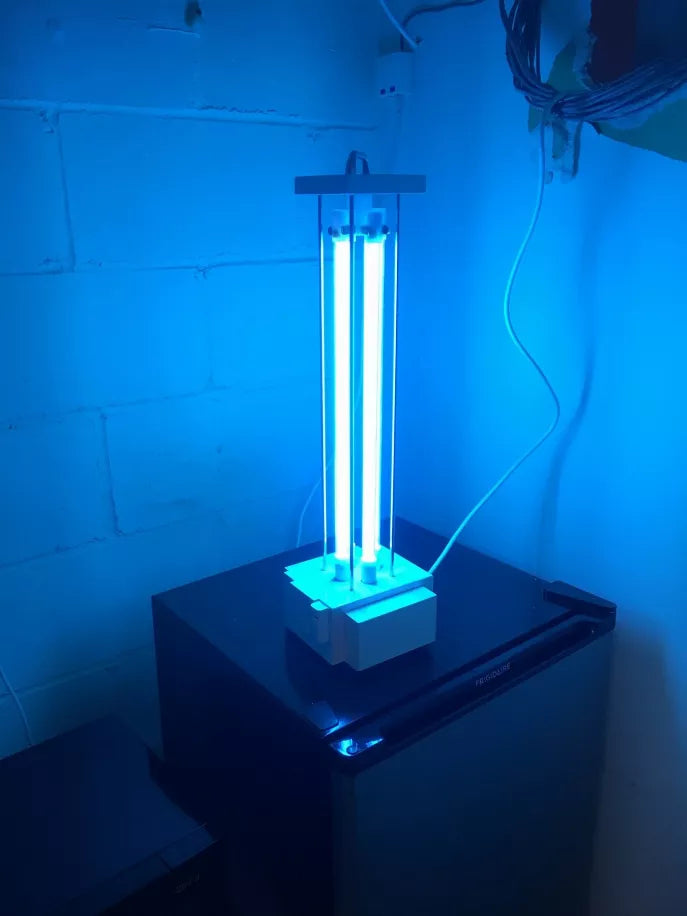 UVC tabletop lamp with blue-glowing UV tubes on dark countertop base