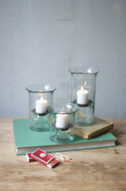 Set of three clear recycled-glass votive cylinders with lit candles inside