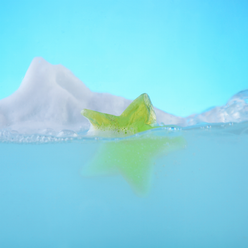 Yellow-green star-shaped soap bar with water splash and reflection