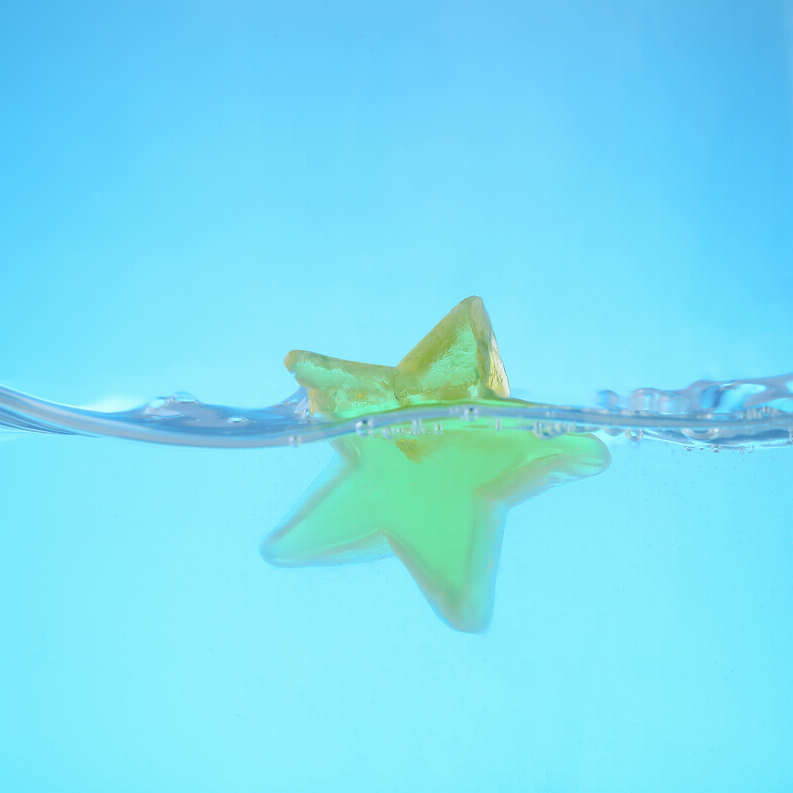 Greenish star-shaped soap bar floating in blue water with bubbles