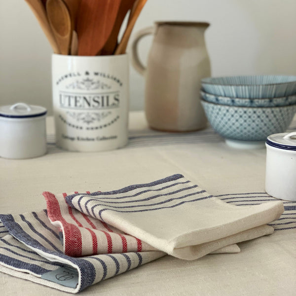 Folded striped tablecloth napkins in cream with navy and red bands