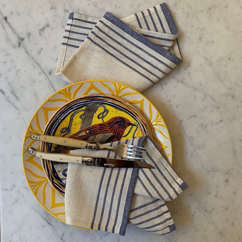 Striped cream napkins with navy lines, folded over plates with cutlery