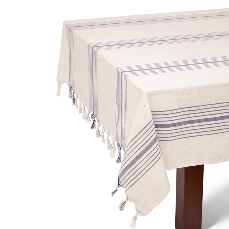 Tablecloth draped on table, cream with navy striped border and fringe