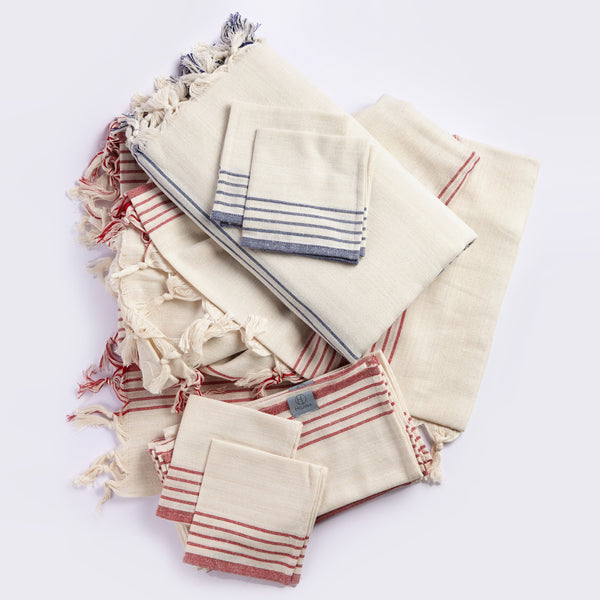 Stacked tablecloth napkins in cream with navy and red stripe patterns