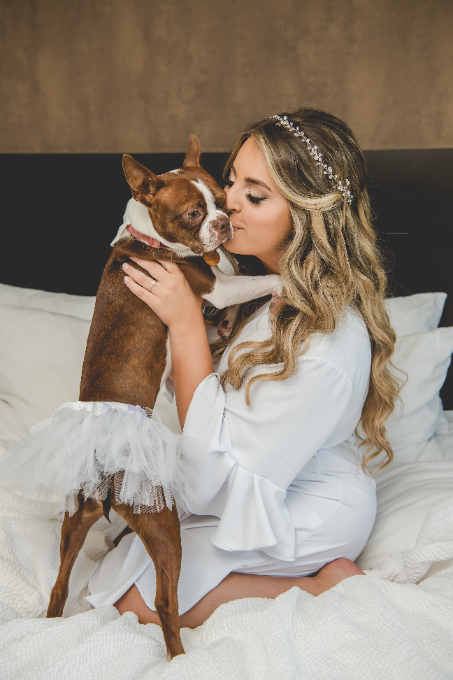 White bridal pet tutu skirt with layered tulle ruffles while held on a bed