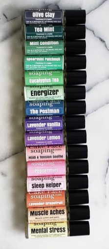 Stack of aroma roll-on bottles with black caps, assorted blend label strips