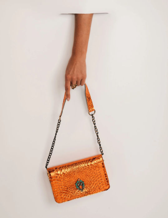 Shiny orange leather crossbody bag with chain strap and front emblem