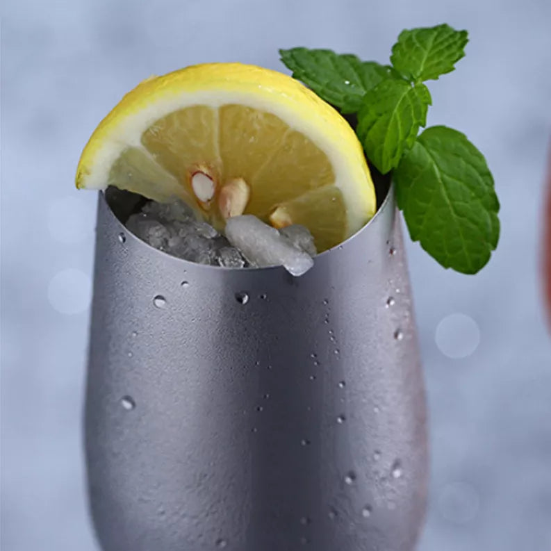Silver cocktail glass filled with ice, topped with lemon wedge and mint leaves