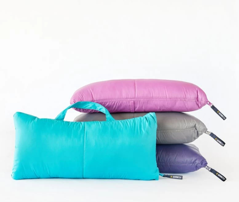 Quilted down throw blankets stacked in multiple colors, including pink and gray