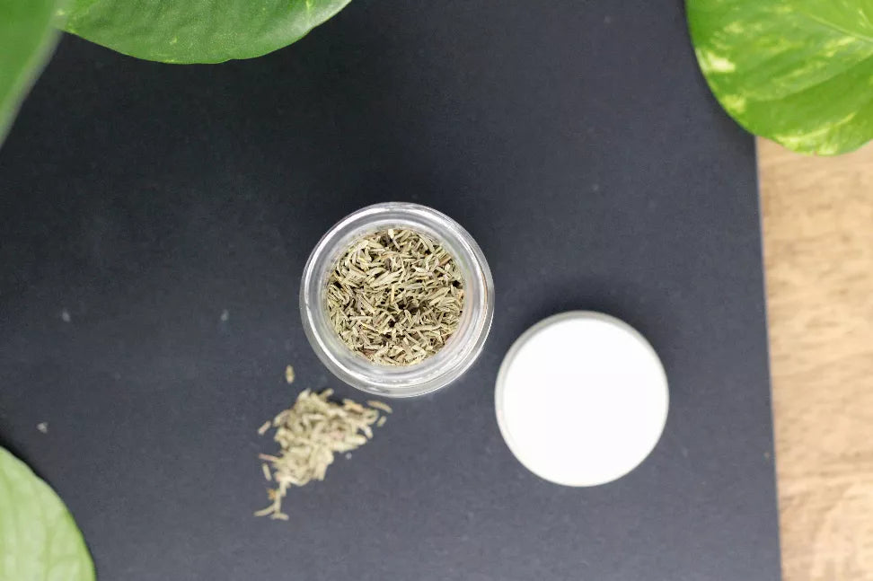 Small glass jar filled with dried thyme leaves