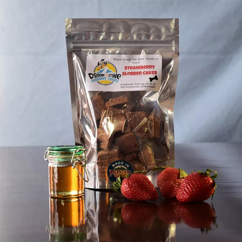 Strawberry slobber cakes dog treats in clear resealable pouch with strawberries