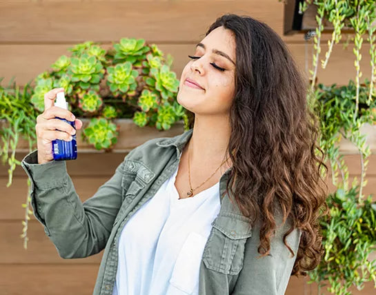 Blue toner bottle with spray nozzle held in hand