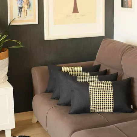 Black houndstooth jacquard throw pillow with yellow center stripe, on sofa