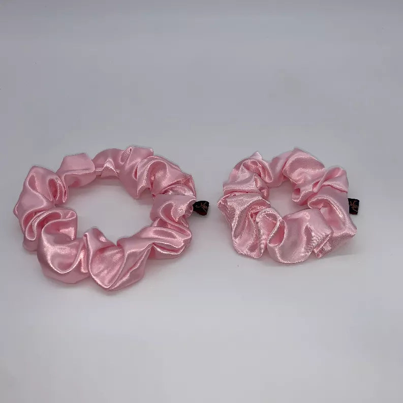 Pair of pink satin scrunchies with circular gathered ruffle texture and fabric tags