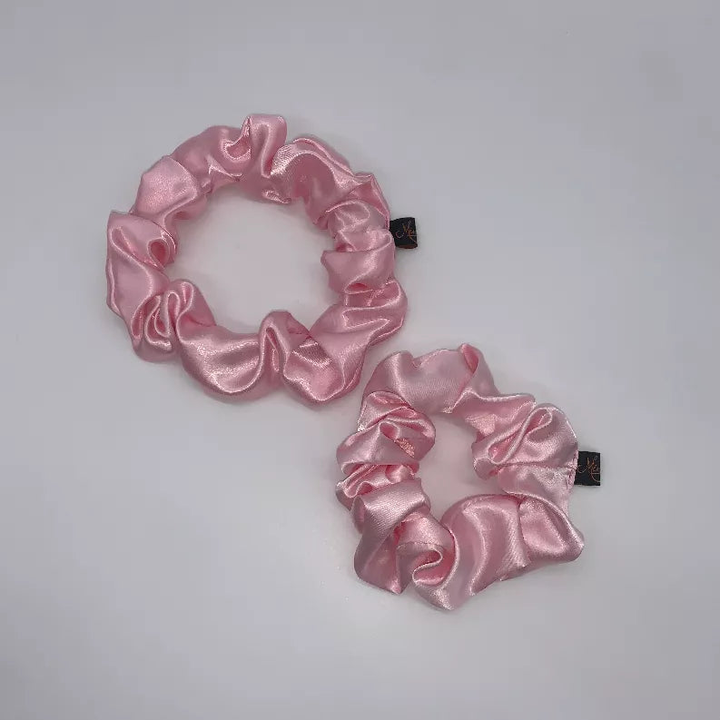 Pink satin scrunchie pair with gathered ruffle loops and small fabric tags