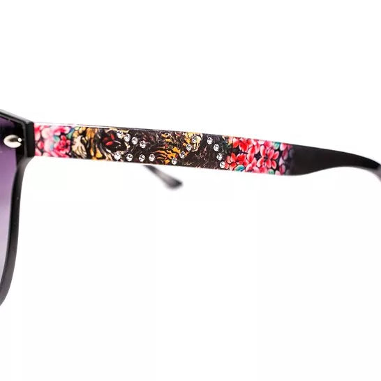 Close-up of sunglasses front frame with colorful tiger-print temple and dark lens.
