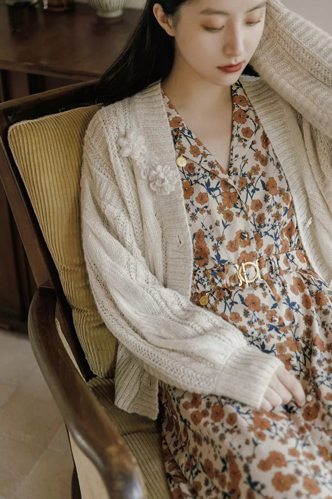 Cream crochet cardigan draped over floral dress, long sleeves, open front