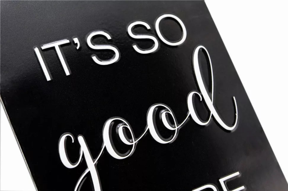Black embossed metal wall sign with white cursive text detail, partial letters