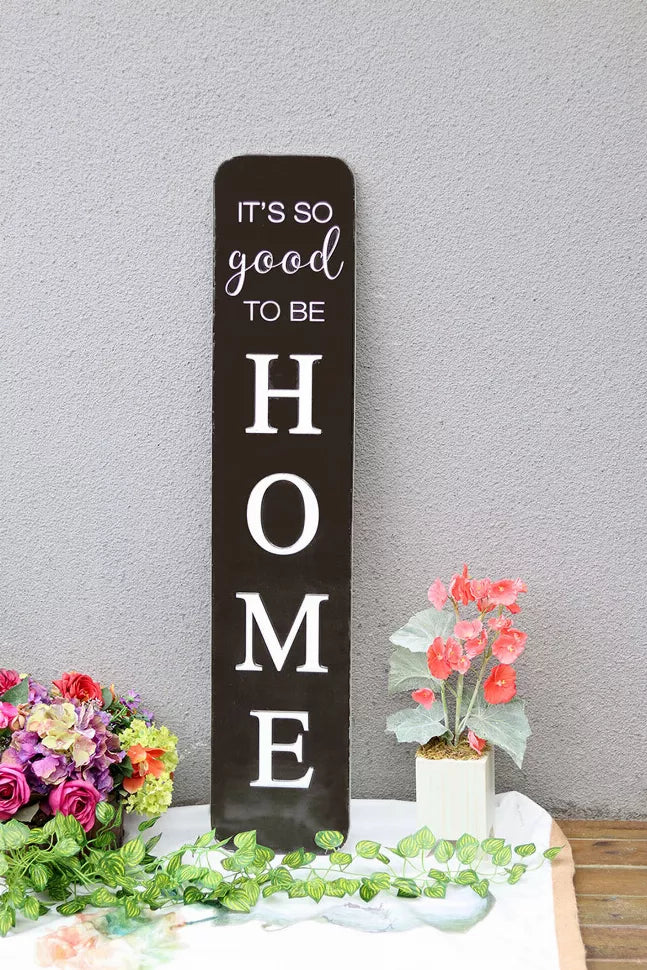 Black embossed metal wall sign reading “HOME” with “It’s so good to be” text