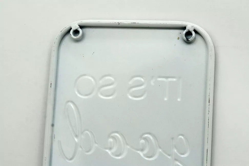 Light gray embossed metal wall sign back with two hanging eyelets and raised text