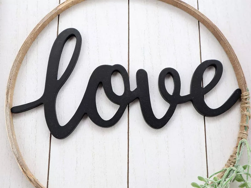 Close-up of round wall sign: black 'love' lettering with green leaves