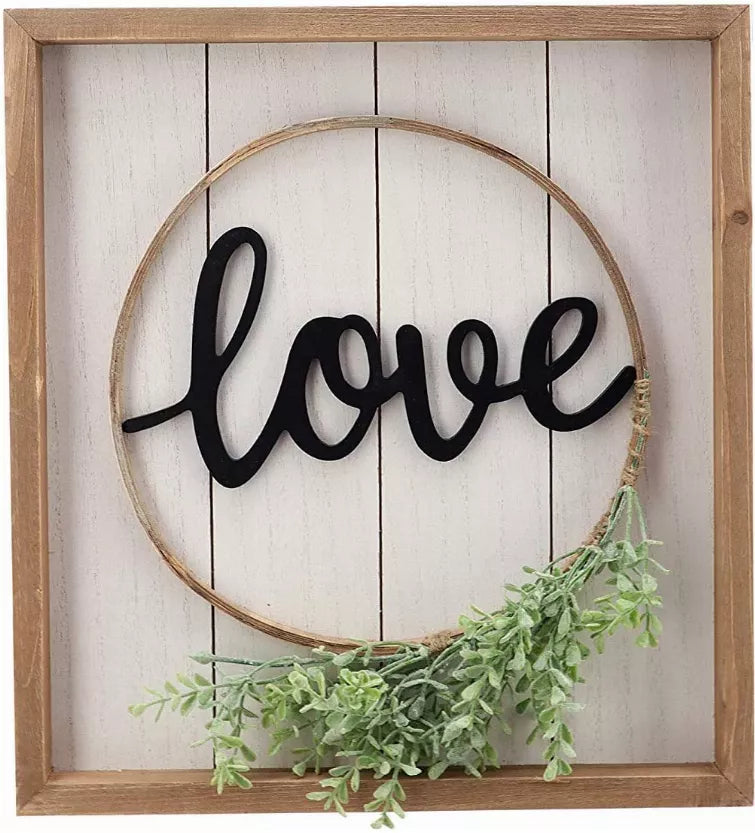 Wood-framed round wall sign with black 'love' and green garland