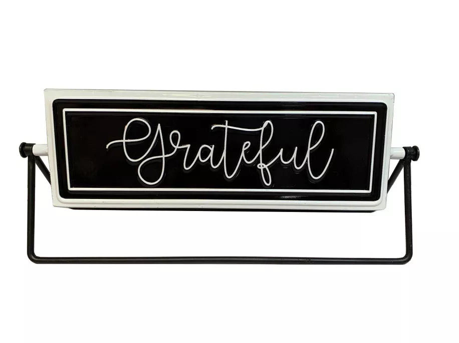 Rotating tabletop metal sign with black panel and white cursive 'Grateful' on black stand